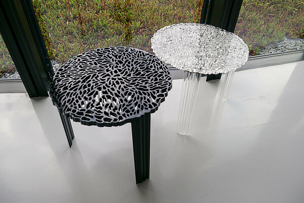 Deux tables basses en plexiglas, l’une est blanche et l’autre noire, prise de vue légèrement en hauteur