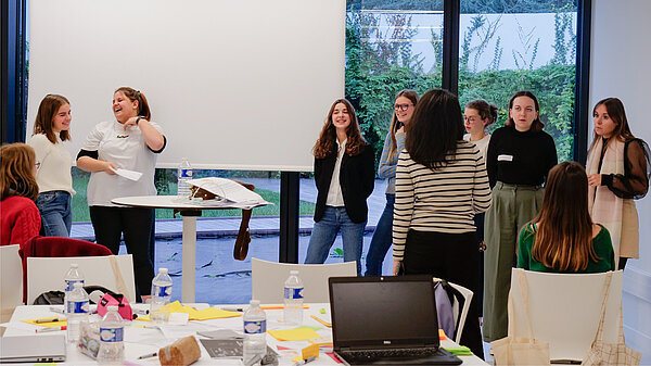 Un groupe de personnes debout dans la salle D, en train de répéter pour un exposé